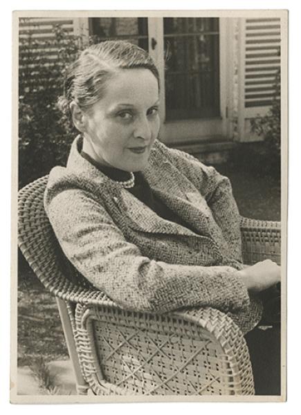 Black and white photograph of Blanche Knopf sitting in a wicker chair outdoors, April 1936.